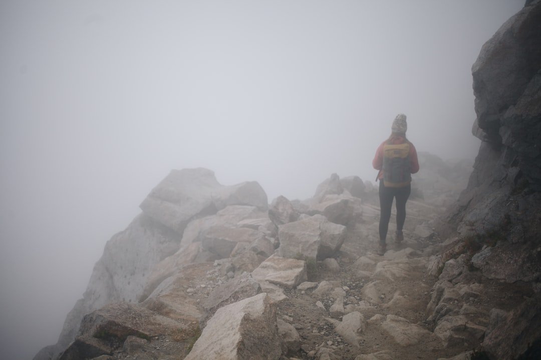 person climbing mountain foggy