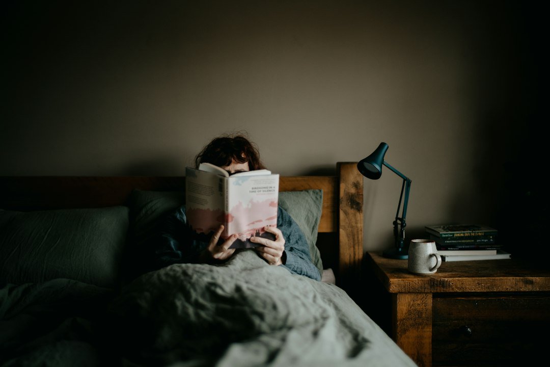 person reading book in bed at night